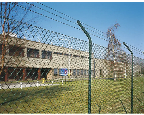 Stängsel med taggtråd framför en byggnad