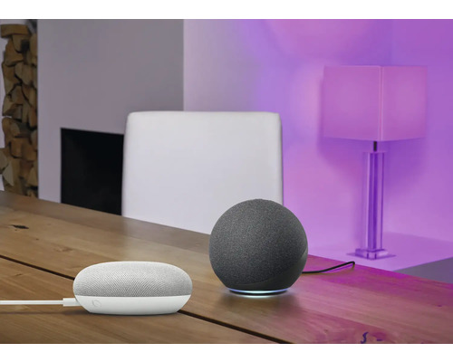 Miljöbild med en grå, sfärisk smart högtalare och en vit smart högtalare på ett träbord