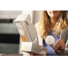 Kvinna håller SMART+ Lighting glödlampa med förpackning