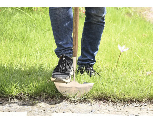 Person som använder en spade i gräset.