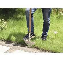 Person med ogräsjärn i gräsmattan.