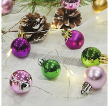 Dekorativa julgranskulor med tallkottar och ljusslinga på tyg