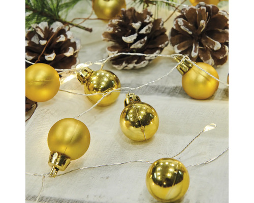 Dekorativ ljusslinga med gyllene kulor och kottar