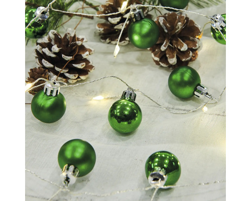 Gröna julgranskulor med tallkottar och ljusslinga