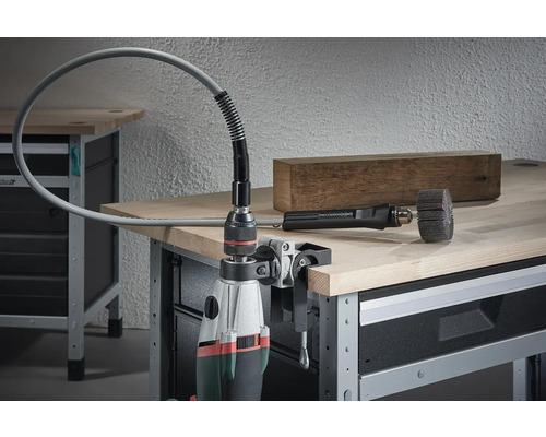 Borrmaskin med monterad flexibel axel och slipverktyg på en arbetsbänk