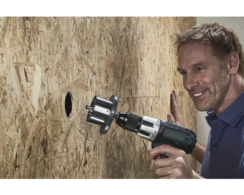 En man borrar ett hål i en träskiva med en hålsåg.