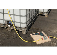 Scen med IBC-behållare, en borrmaskin och en slangpump på en bräda.