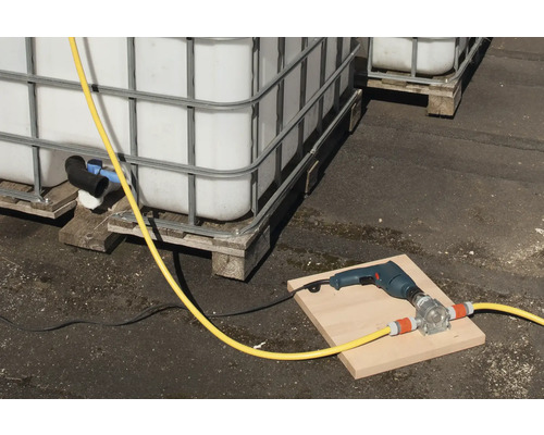 Scen med IBC-behållare, en borrmaskin och en slangpump på en bräda.