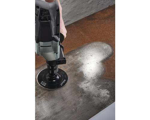 En person slipar en metallyta med en slipmaskin.