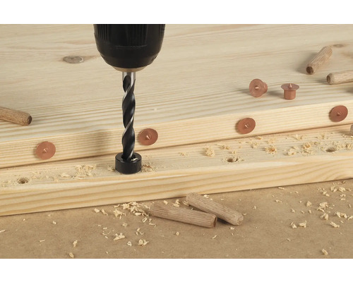 Borrmaskin med pluggborr borrar hål i en träskiva med markeringar