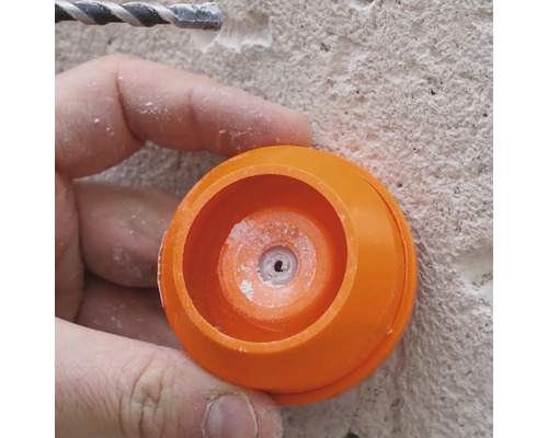 Närbild av en person som arbetar med en borr och ett orange dammskydd