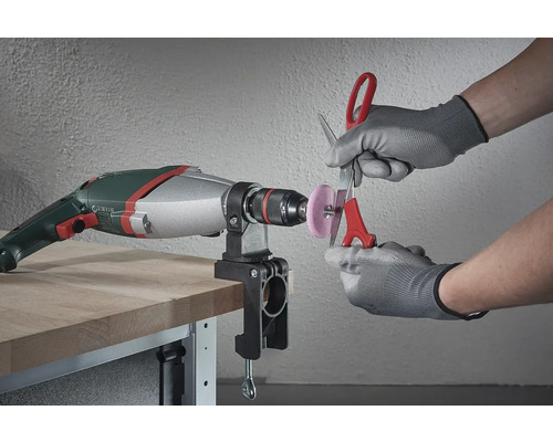 En borr med ett monterat slipfäste används för att vässa en sax.