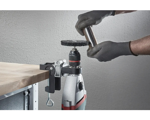 En borrmaskin med slipskiva och arbetsstycke på en arbetsbänk.