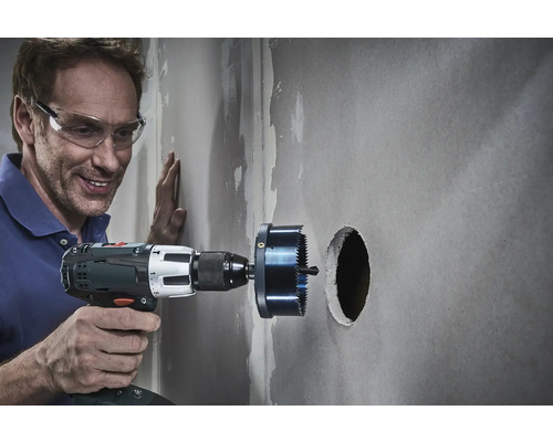 Hantverkare borrar ett hål i en vägg med en hålsåg