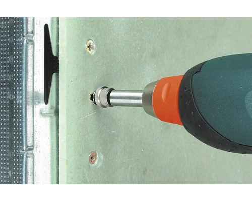 Detaljvy av en skruvmejsel som skruvar en skruv i en gipsskiva fäst på en metallram.