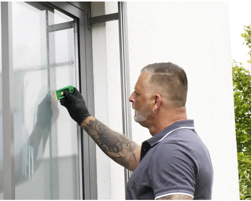 En person använder en glasskrapa för att rengöra en fönsterruta.