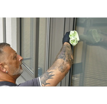 Man med tatueringar rengör fönster med en trasa