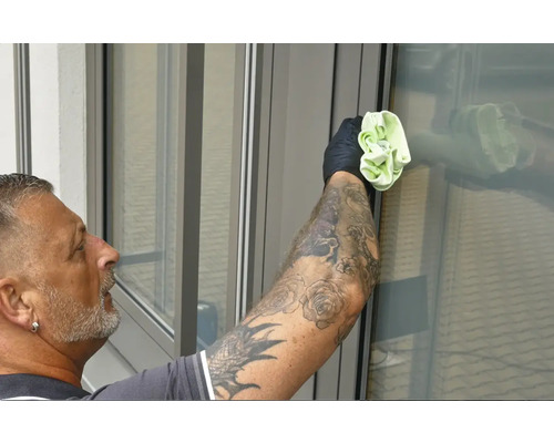 Man med tatueringar rengör fönster med en trasa