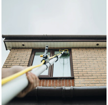 Fönsterrengöring med teleskopborste på ett hus