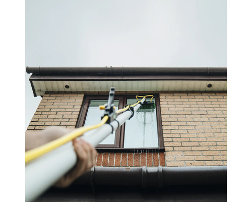 Fönsterrengöring med teleskopborste på ett hus
