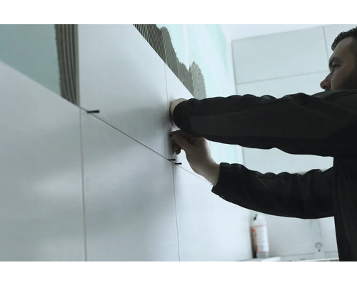 Kakelsättare som arbetar med kakel och kakelsnören