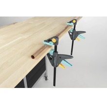 Arbetsbänk med två Wolfcraft enhandsspännen och ett kopparrör.