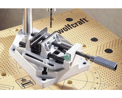 Wolfcraft logotyp. Borrstativ med skruvstäd på en arbetsbänk
