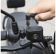 En person använder en skruvmejsel med vinkelhuvud för att arbeta på en motorcykel.