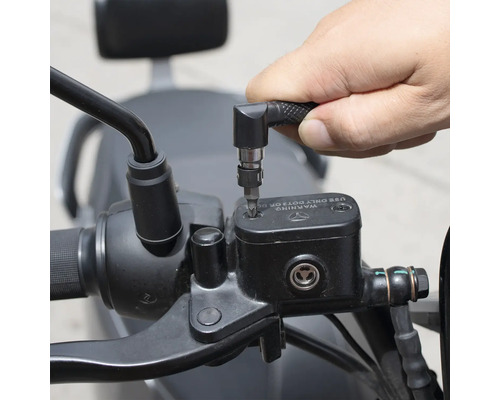 En person använder en skruvmejsel med vinkelhuvud för att arbeta på en motorcykel.