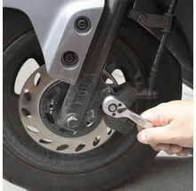 En person använder en spärrnyckel på en motorcykel.