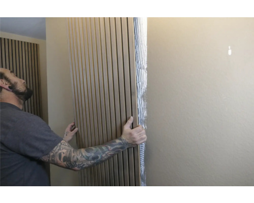 Man fäster akustikpaneler på väggen för ljudabsorption och väggdesign.