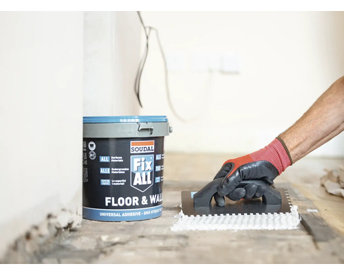 En hink med Soudal Fix ALL-lim och en person som applicerar lim med en spackel.