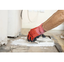 Plattsättare applicerar lim på plattor