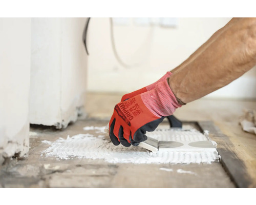 Plattsättare applicerar lim på plattor