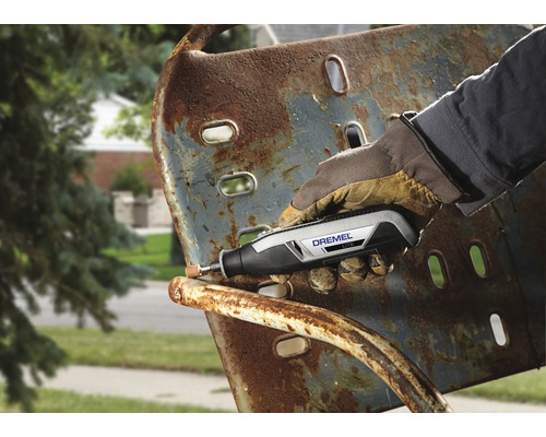 En person använder ett Dremel-verktyg för att ta bort rost från en metallstol.