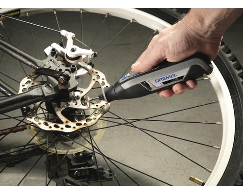 Dremel logotyp. En person använder ett Dremel Lite verktyg på en cykelbromsskiva.