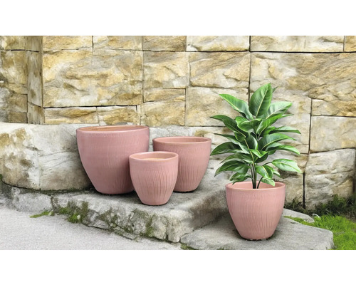 Blomkrukor i olika storlekar framför en stenmur