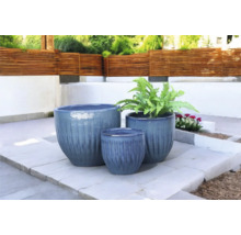 Tre blomkrukor i olika storlekar på en terrass