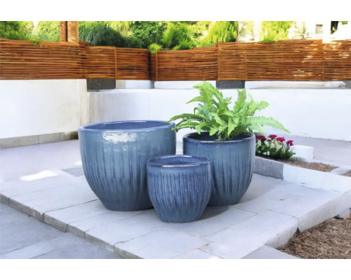 Tre blomkrukor i olika storlekar på en terrass