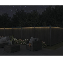 Kvällsträdgårdsscen med upplyst trästaket och trädgårdsmöbler