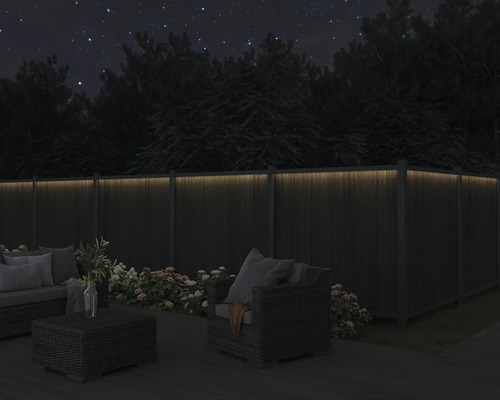 Kvällsträdgårdsscen med upplyst trästaket och trädgårdsmöbler