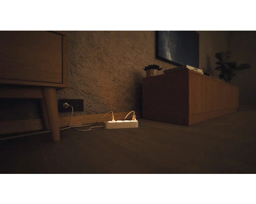 Grenuttag med anslutna strömkablar i ett vardagsrum.