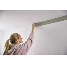 Kvinna målar tak med färgroller