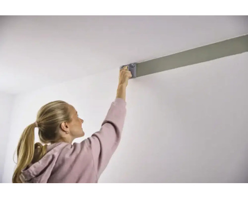 Kvinna målar tak med färgroller