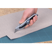 En hand skär kartong med en universalkniv.