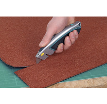 En matta skärs till med en mattkniv.