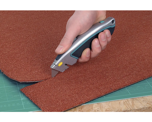 En matta skärs till med en mattkniv.