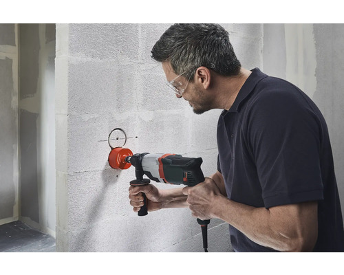 Man borrar ett hål i en vägg med en hålsåg.