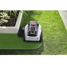 Robotgräsklippare som underhåller en gräsmatta i en trädgård.