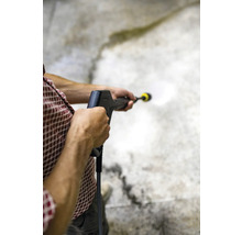 En person använder en högtryckstvätt för att rengöra en yta.